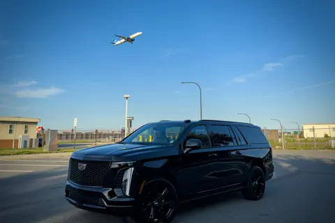 DV Executive black Cadillac Escalade ESV near the airport as a jet takes off overhead